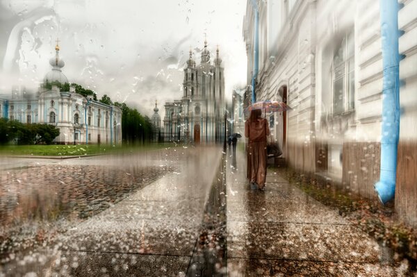 A girl in a long raincoat under an umbrella in St. Petersburg
