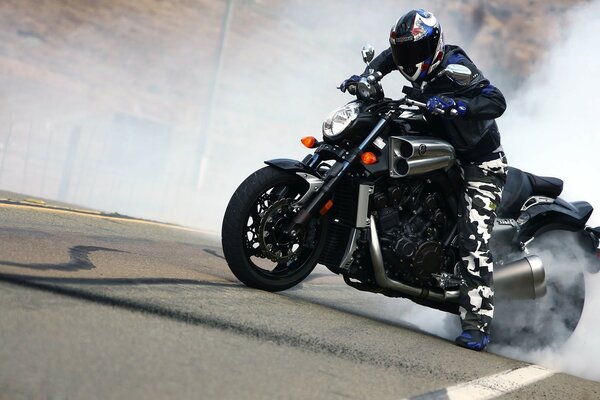 A real biker on the track is drifting, the wheels are already smoking