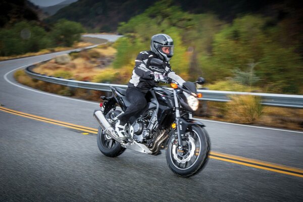 Biker on a Honda motorcycle on the highway in autumn