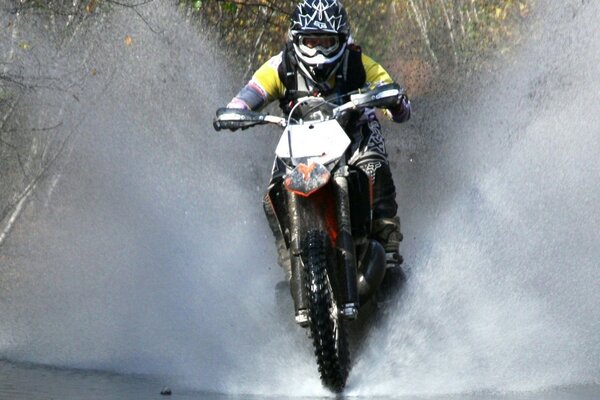 A rider on a motorcycle jumps through the water