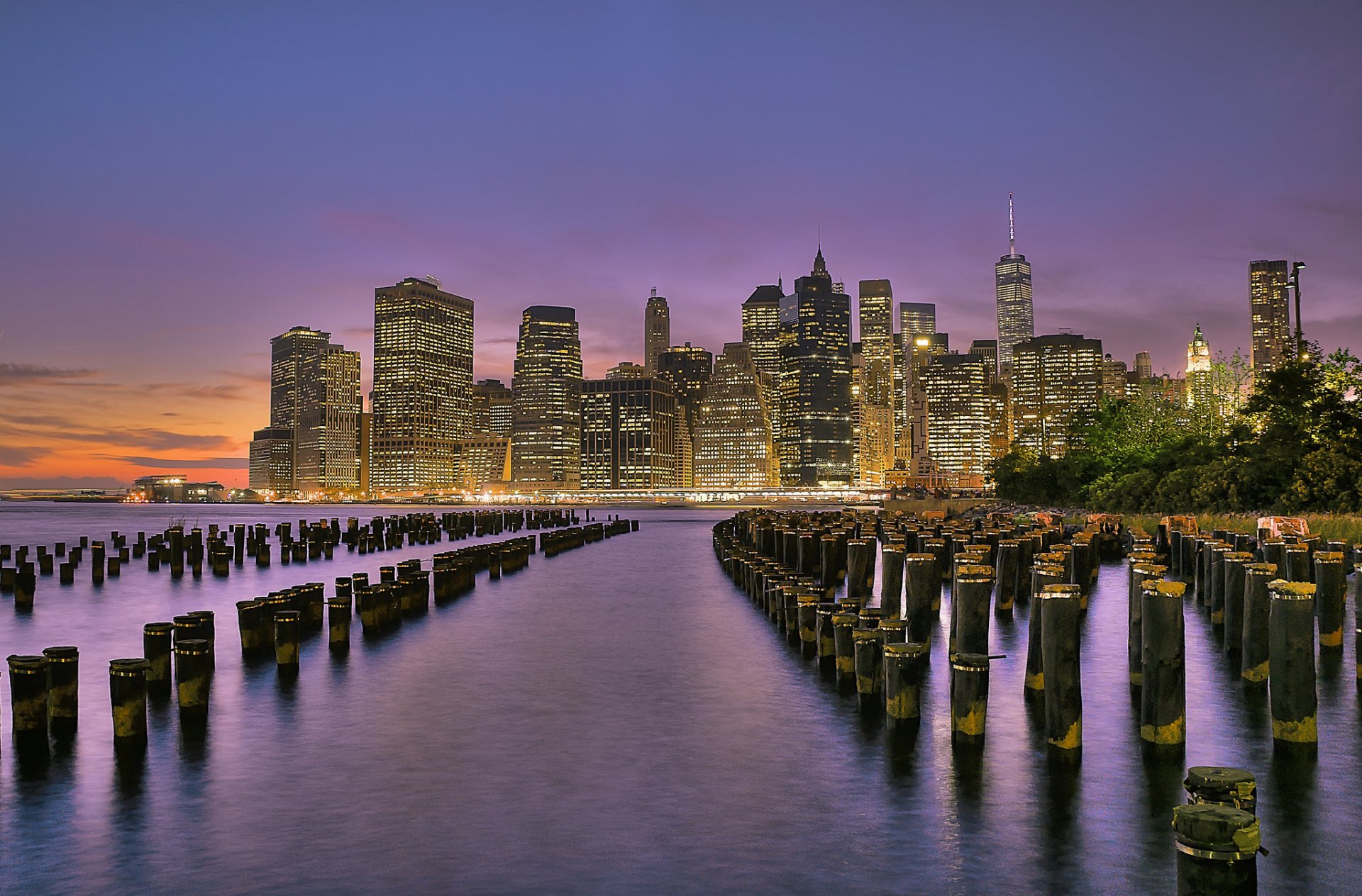 nowy jork usa brooklyn bridge park dolny manhattan east river miasto światła drapacze chmur budynki rzeka filary brzeg wieczór zachód słońca pomarańczowy fioletowy niebo