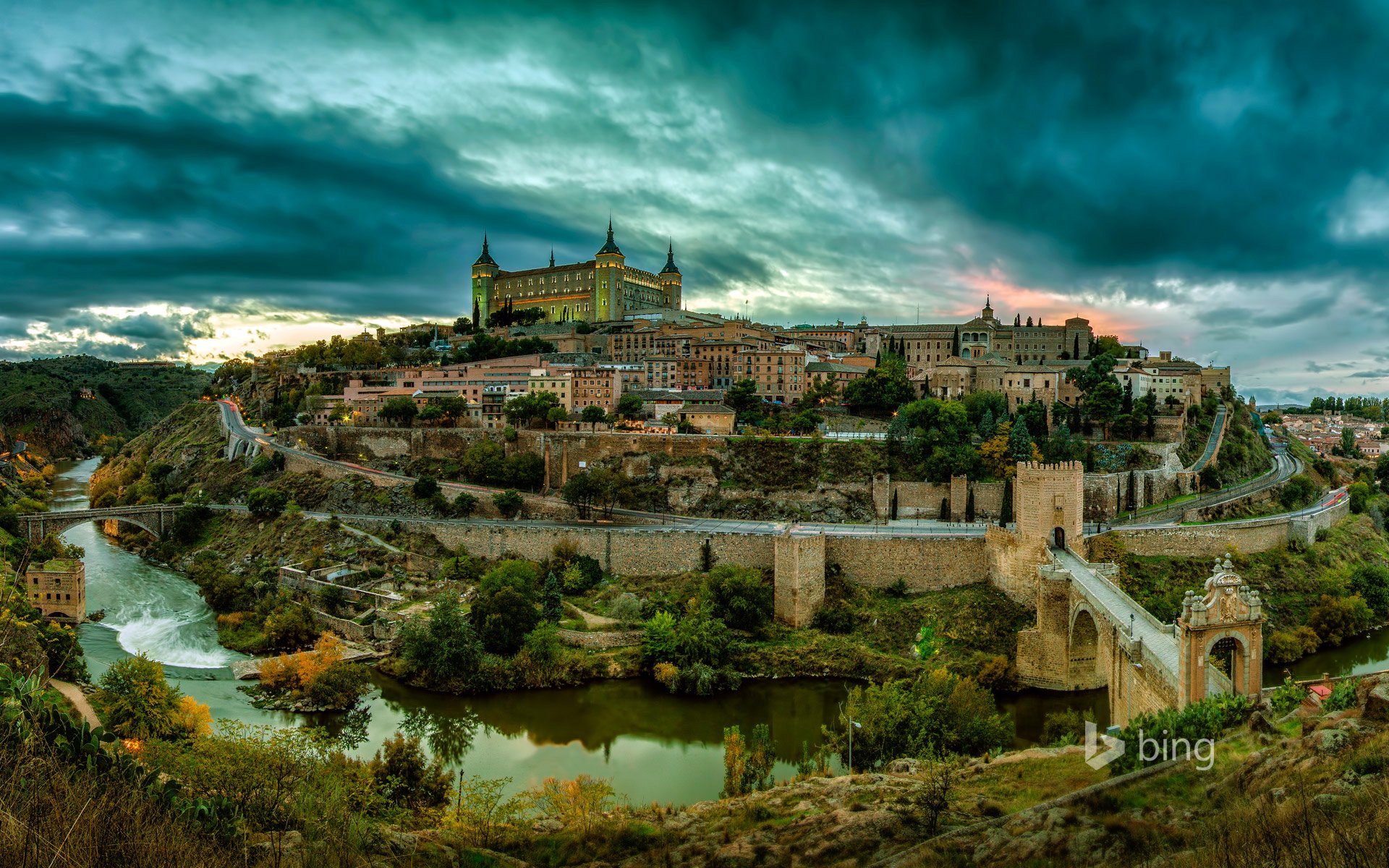 tolède espagne paysage colline château maisons tour arbres ciel nuages coucher de soleil rivière pont