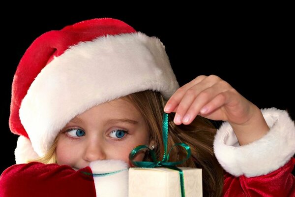 Das Mädchen in der Mütze packt das Geschenk aus