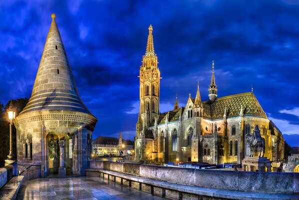 In the city of Budapest, the Matthias Church is illuminated in the evening by the lights of the city
