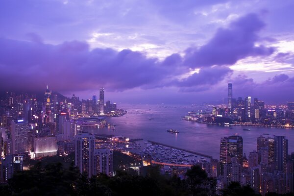 Victoria Harbor in lilac tones. Victoria Harbour Bay. Landscape of Hong Kong, China. Lighting of the night city of Hong Kong. Opening view of skyscrapers under the open night sky