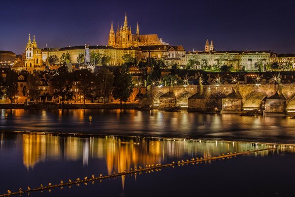 La ciudad nocturna de Praga se refleja en el río Moldava