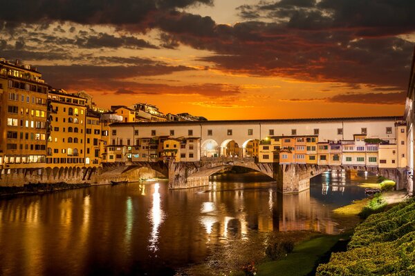 An Italian city over a river with a sunset sky