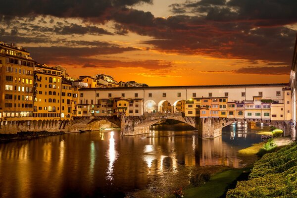 Una ciudad italiana sobre un río con un cielo al atardecer