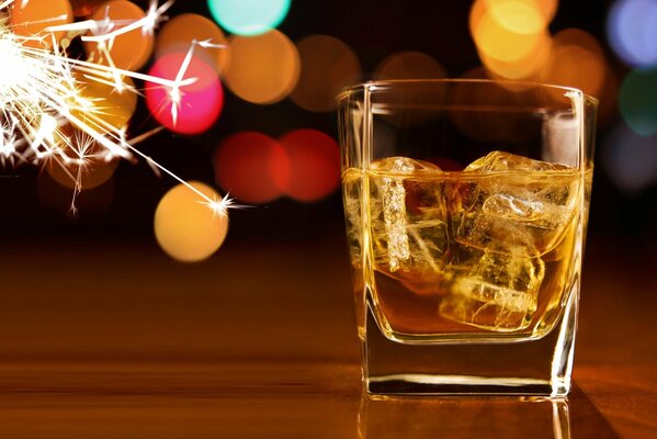 Un vaso de whisky y hielo iluminado por la luz de la Bengala