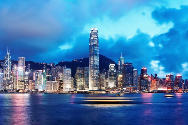 Vista nocturna desde el mar a los edificios altos de Hong Kong