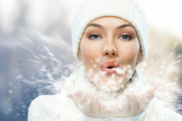 A girl blows snow off her hands in winter