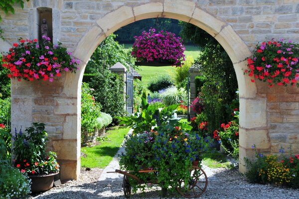 A garden with a cart and an entrance through an arch