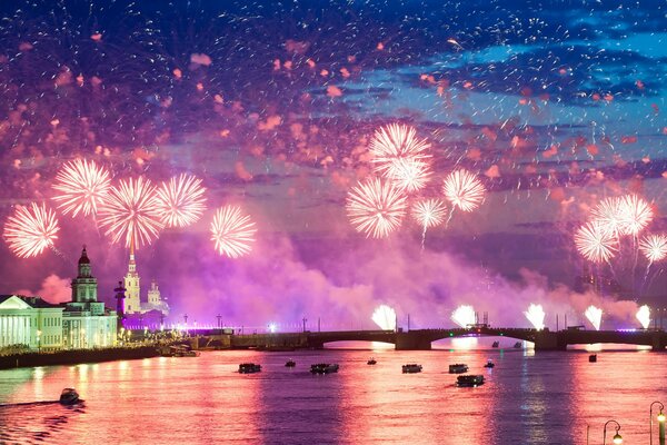 Night city on the background of colorful fireworks reflected in the water