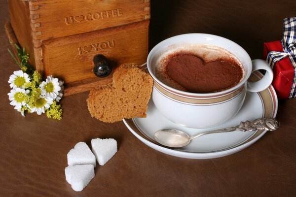 Heißer Kaffee in einer Tasse mit einer Prise Schokolade in Form eines Herzens