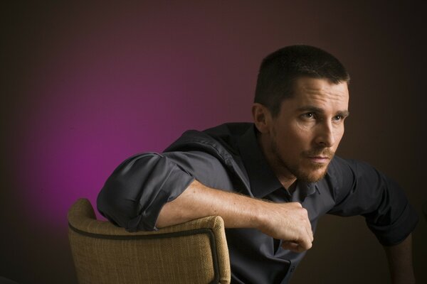 Christian Bale acteur sur la photo est assis sur une chaise