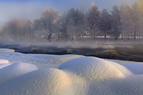 Winter landscape, snowdrifts on the river bank, forest