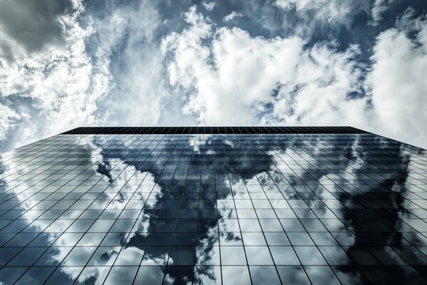 Reflection of clouds in a tall glass building