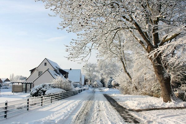 Winterstraße im Dorf entlang des Zauns