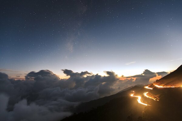 Cielo al tramonto con nuvole basse e strada su una collina con luci