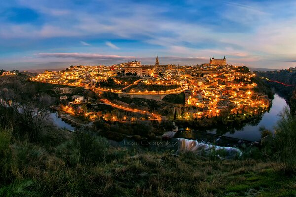 Evening city, sparkling with lights in the ring of the river and emerald greenery