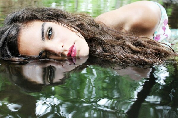 A girl with makeup in the reflection of water