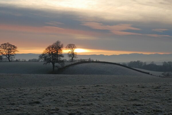 Paisaje de invierno con puesta de sol en el campo