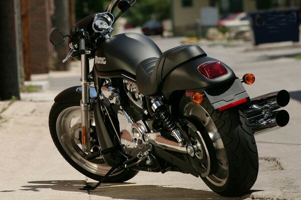 Стоящий на подножке современный мотоцикл марки harley davidsonчёрного цвета