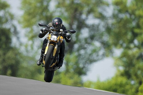 A motorcyclist on one wheel rushes along the highway