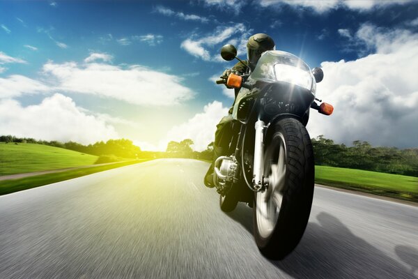 Una motocicleta recorre la carretera en medio de la puesta de sol