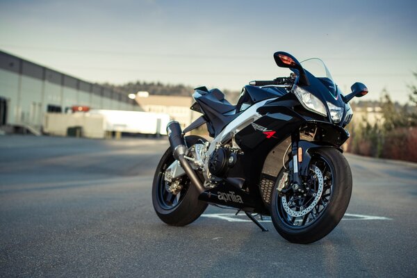Aprilia s black sports motorcycle stands on the asphalt