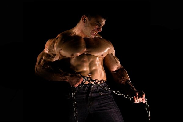 A man with a naked torso holds a chain in his hands