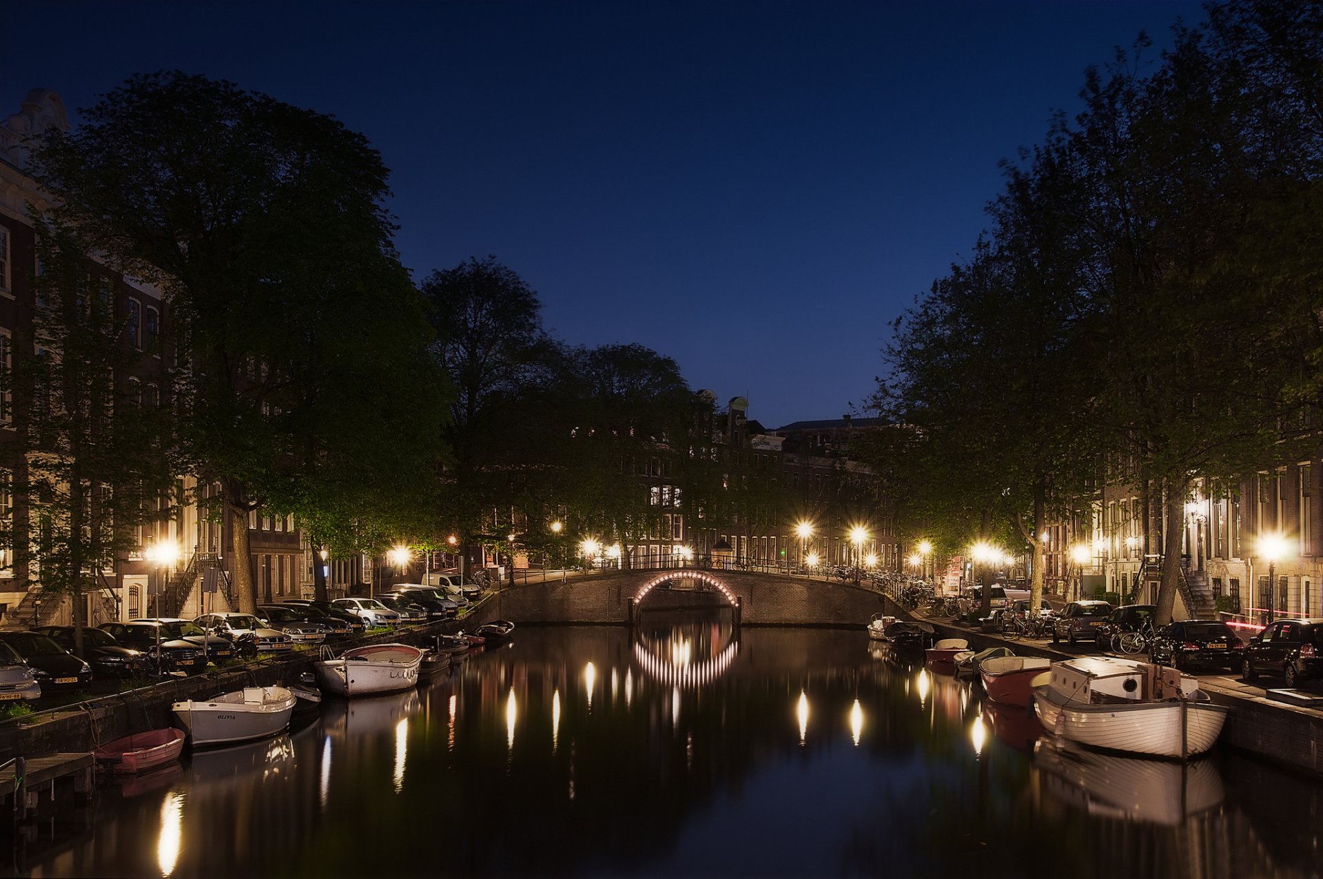 holandia amsterdam ulica samochody kanał łodzie noc światła latarnie odbicie