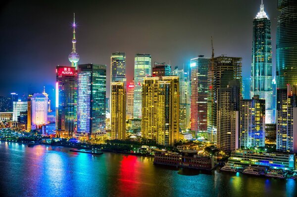 La ciudad nocturna de Shanghai se ilumina con luces y se refleja en el río