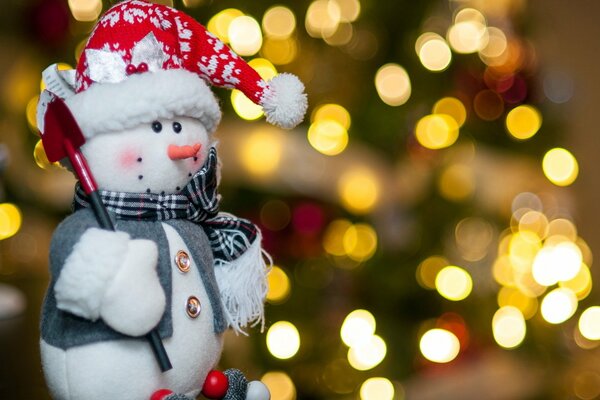 Pupazzo di neve giocattolo con pala davanti all albero di Natale