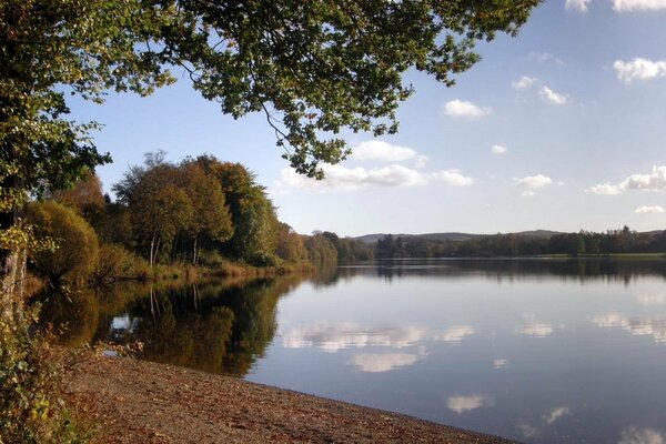 Autumn lake shore with reflection of clouds in the lake