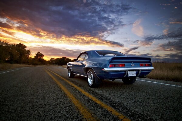 Camaro cavalca lungo la strada e davanti al tramonto