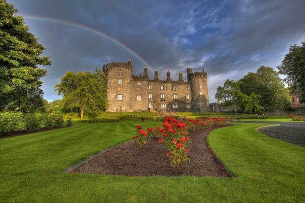 A castle in Ireland with a rainbow and flowers