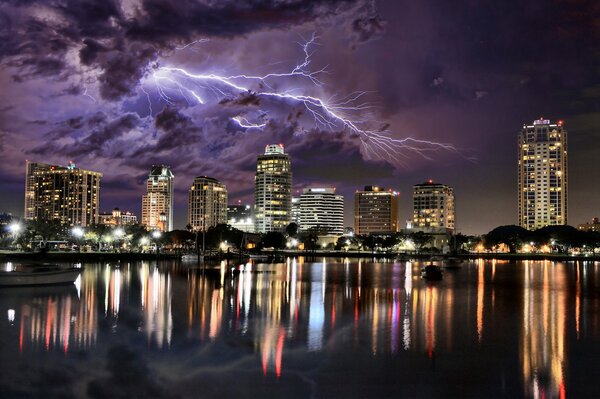 The city is next to the river. Night sky with thunderstorm