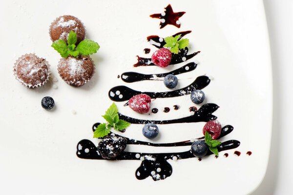 A plate decorated with a Christmas tree with cupcakes and berries