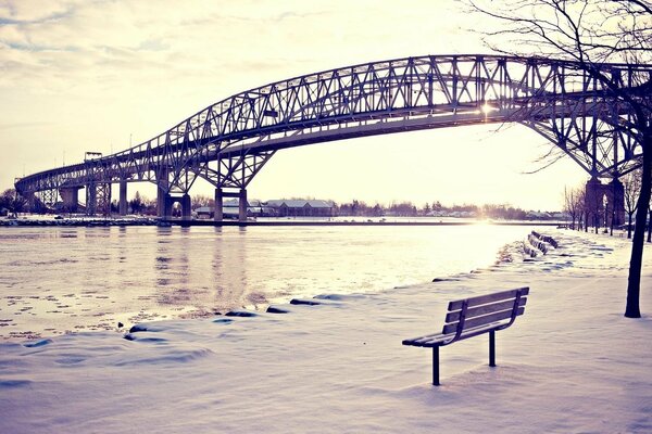 Vista del puente, el río y el banco en la nieve