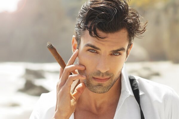 A young man with a cigar on the background of the sea
