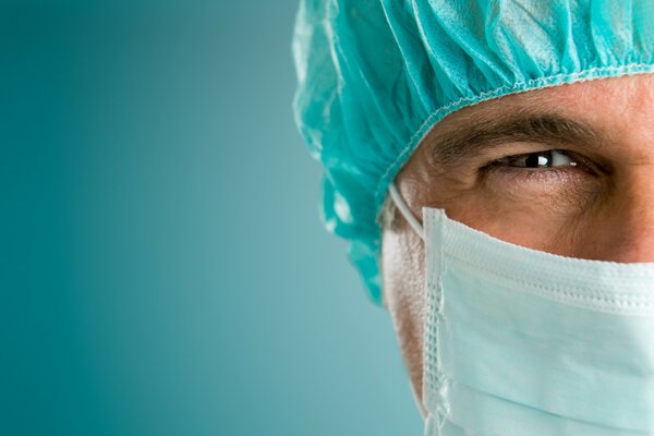 Лицо врача в маске на голубом фоне