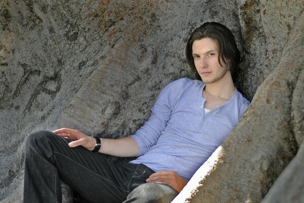 Ben Barnes is lying on a rock