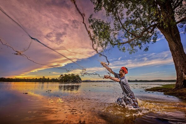 Pêcheur au coucher du soleil pêche avec un filet