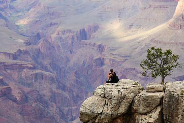 Un homme assis sur une falaise dans un beau Canyon