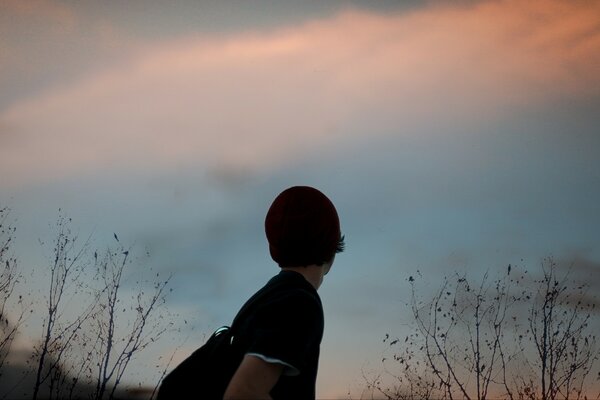 A boy with a winter hat looks at the sky