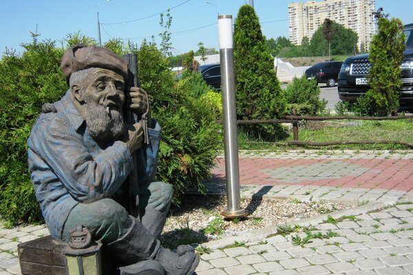 Monument to the grandfather in an earflap with a gun