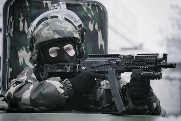 Zamaskowany żołnierz sił specjalnych strzela z karabinu maszynowego