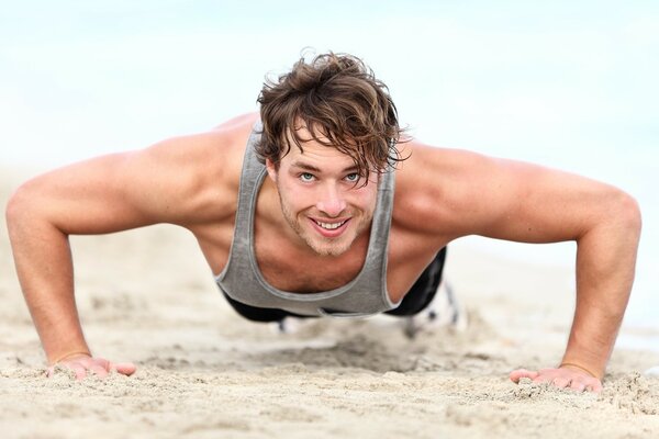 Muscles of a man doing push-ups on the sand