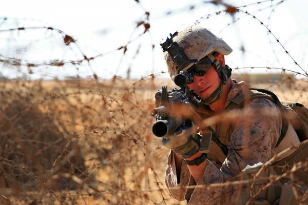 A soldier with a weapon behind barbed wire